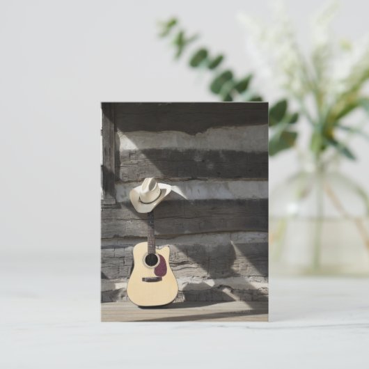 ログキャビンに寄り掛かるギターのカウボーイハット ポストカード (スタンド正面)