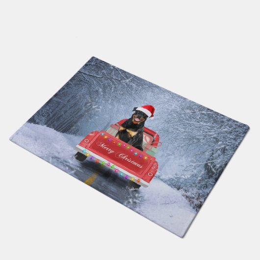 ロットワイラーの犬が雪の中でクリスマストラックに座って ドアマット (アングル)