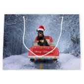 ロットワイラーの犬が雪の中でクリスマストラックに座って ラージペーパーバッグ (正面)