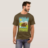 ワイオミング州の山々をバックにバイソンをサーフィンさせる面白Tシャツ Tシャツ (正面フル)