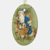 冬の雪の中で鹿とクリスマスプレゼントを持つサンタ セラミックオーナメント (左)