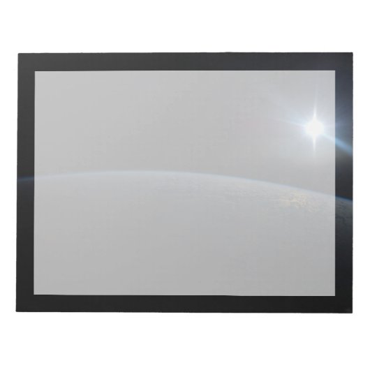 地球の地平線上に沈む太陽。 ノートパッド (正面)