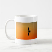 壮大なフリゲート飛んでいる鳥のオレンジ色の夕日 コーヒーマグカップ (左)