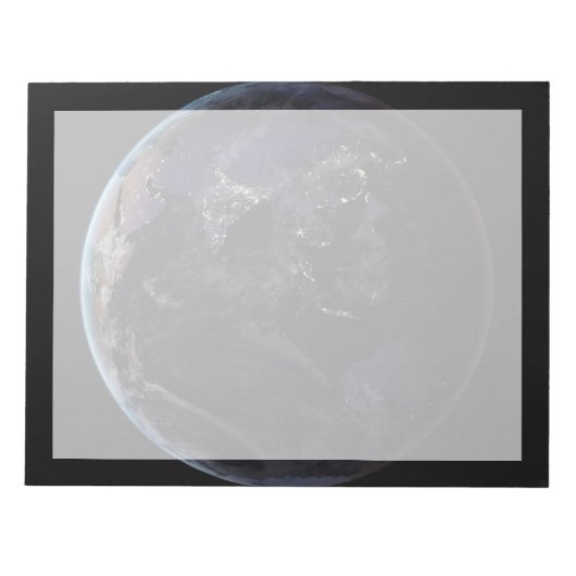 夜にアジアの都市の光を示す完全な地球。 ノートパッド (正面)