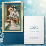 天使と鹿のギフト ヴィンテージクリスマスカード シーズンカード<br><div class="desc">美しいヴィンテージクリスマスカードの画像で、リンゴの籠と人形を持った小さな鹿と天使が描かれています。天使はクリスマスツリーを持ち、ドアをノックしようとしています。この画像はきれいに整えられ、金色の光りがかった背景に置かれ、青い枠線で囲まれています。昔ながらの方法でホリデーシーズンを祝うのは楽しいことです! このカードの左側は青い色合いが同じで、右側には簡単にお好きなメッセージと署名を入れることができます。</div>