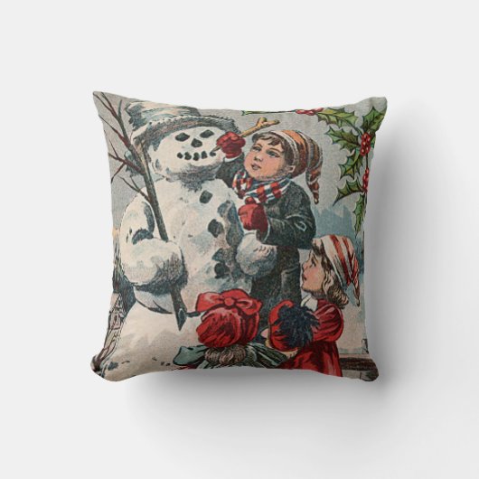 子供たちが雪だるまとセイヨウヒイラギを作っています クッション (正面)