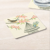 小さな鳥が枝に止まり鳥籠に止まる スクエアペーパーコースター (アングル)