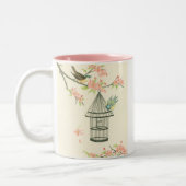 小さな鳥が枝に止まり鳥籠に止まる ツートーンマグカップ (左)