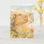 平和な牧草地で休むケイピバラ カード (黄色い花)