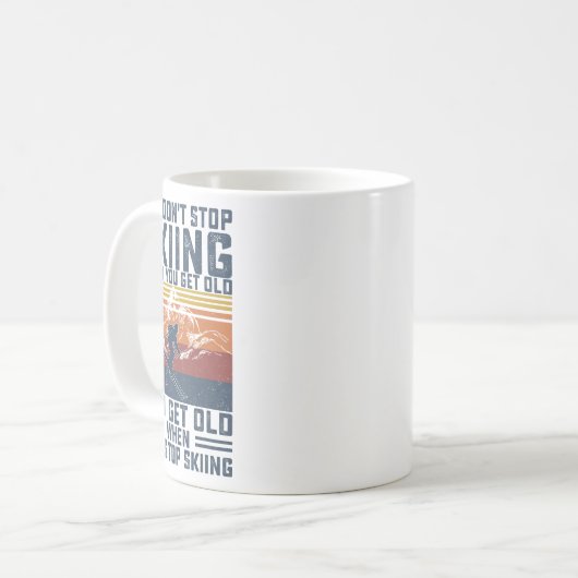 年をとったらスキーをやめるわけじゃない、スキーヤーはスキーを続ける コーヒーマグカップ (正面左)