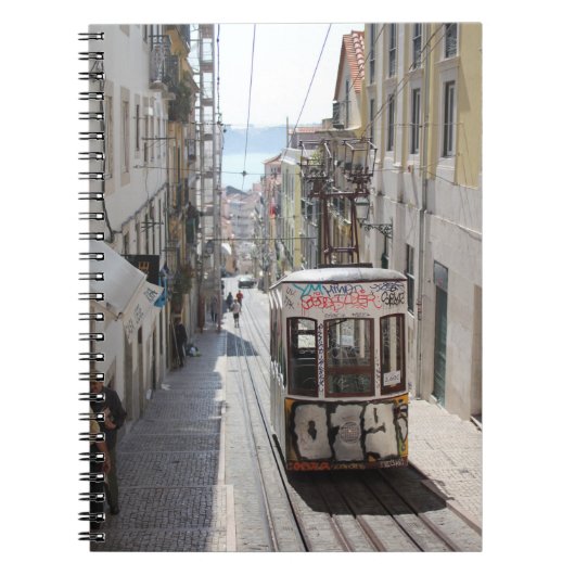 建物沿いの鉄道上の灰色の路面電車 ノートブック (正面)