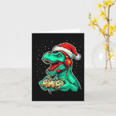 恐竜のTレックスがビデオゲームをプレイするサンタ帽子クリスマス カード (黄色い花)