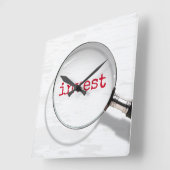 拡大鏡の下の「Invest」テキスト スクエア壁時計 (傾斜)