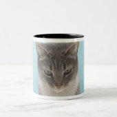敷物のおもちゃのマウスを見ている猫 ツートーンマグカップ (中央)