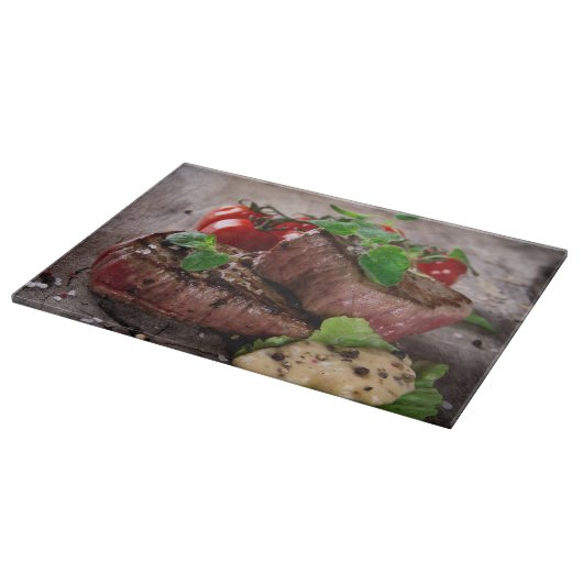 新しいハーブおよびトマトが付いている焼かれたbbqのステーキ カッティングボード (角)