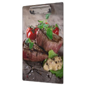 新しいハーブおよびトマトが付いている焼かれたbbqのステーキ クリップボード (左)