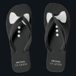 新郎。おもしろいホワイトボウタイ&ボタ結婚ン ビーチサンダル<br><div class="desc">この可愛いビーチサンダルは、新郎が靴とパーティーを蹴り落とす準備ができている時に最適だ。白い蝶ネクタイと上部のボタンと彼の名前とタイトルの下に置かれた可愛いモックタキシードデザインを特徴とする。</div>
