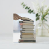 本の積み重ねからの本を取る人の手 ポストカード (スタンド正面)