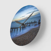 海岸線と防波堤の上の夕暮れの空 ラウンド壁時計 (傾斜)