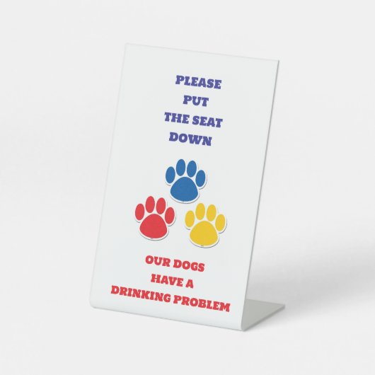 犬はトイレに「飲む問題」の看板を持っている 台座サイン (正面)
