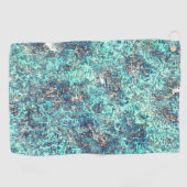 白っぽい灰色のラフの上に金色のオレンジ色で覆われた ゴルフタオル (横)