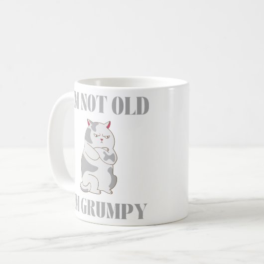 私は年をとってない猫の皮肉なギフトを不機嫌に言う コーヒーマグカップ (正面左)