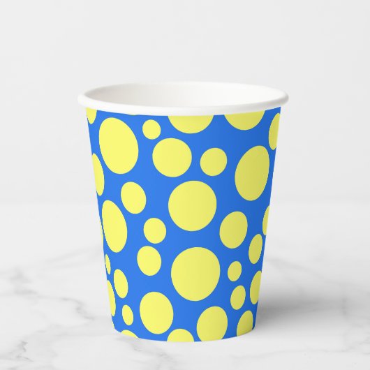 空の青い背景に黄色いエンドウ豆 紙コップ (正面)