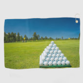 緑のフィールドにゴルフボールのピラミッドのゴルフタオル ゴルフタオル (横)