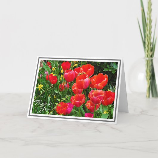緑の葉に対する明るい赤いチューリップ カード (正面)