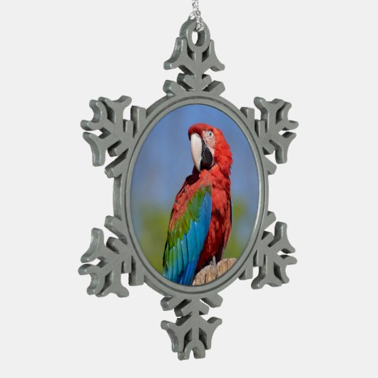 緑色の翼を持つマカオが止まっている スノーフレークピューターオーナメント (左)