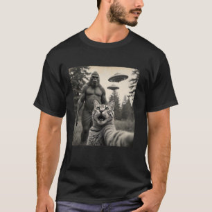 背景おもしろいにサスカッチUFOを持つ猫の自撮り Tシャツ