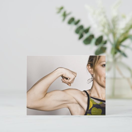 若いブロンドの女性は二頭筋を曲げる一方 ポストカード (スタンド正面)