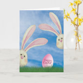 草の中にピンクの卵を持つイースターバニー カード (黄色い花)