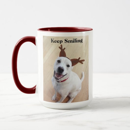 赤いクリスマスを祝う微笑みを浮かべる白犬 マグカップ (左)