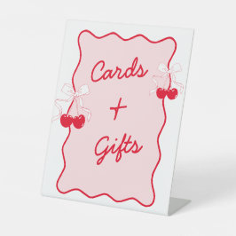 赤とピンクの波状さくらんぼの弓状カードとギフト 台座サイン