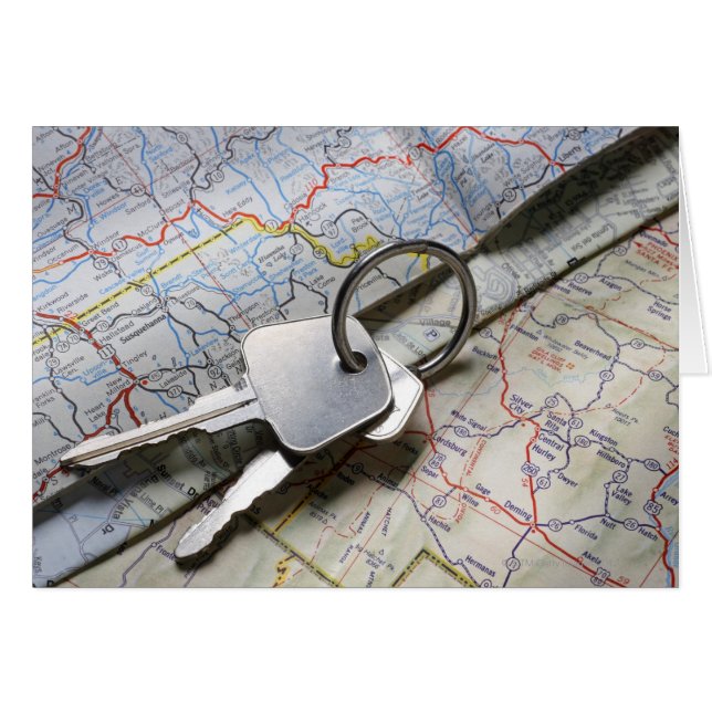 道路地図の山の上に車の鍵のセット。 (正面横)