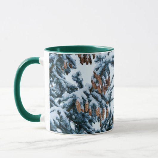 雪で覆われた松の枝とコーン マグカップ (左)