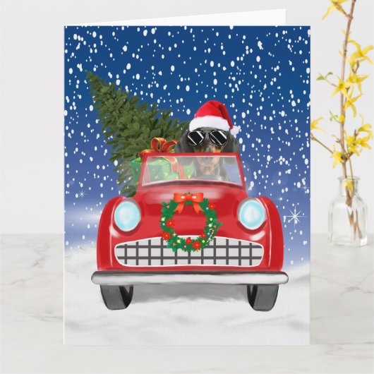 雪のクリスマスに車を運転するダックスフンド犬,  カード (黄色い花)