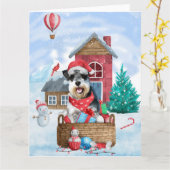 雪のクリスマス犬小屋にいるシュナウザー犬 カード (黄色い花)