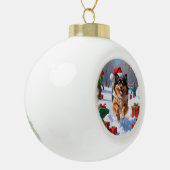 雪の中で走Keeshond Dog Hatとクリスマスハット セラミックボールオーナメント (左)