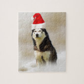 雪の中にサンタハットを持つシベリアのハスキー犬 ジグソーパズル (縦)