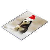 雪の中にサンタハットを持つシベリアのハスキー犬 ノートブック (左側)