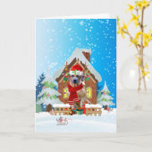 雪の中のクリスマスプレゼントを抱えたローデシアン・リッジバック カード (黄色い花)