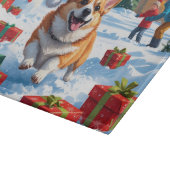 雪の中を走るコーギーとクリスマス帽 カッティングボード (角)