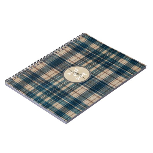 青いフランネルの背景のモノグラム ノートブック (左側)