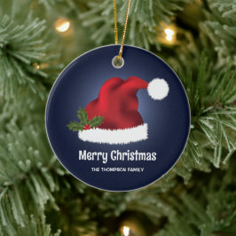 青い背景にクリスマスホーリー付きの赤いサンタ帽子 セラミックオーナメント