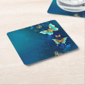青い背景にチョウが黄金色に スクエアペーパーコースター (アングル)
