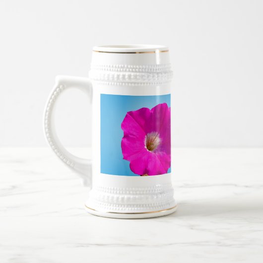 青い背景にピンクのペチュニアの花。 ビールジョッキ (左)