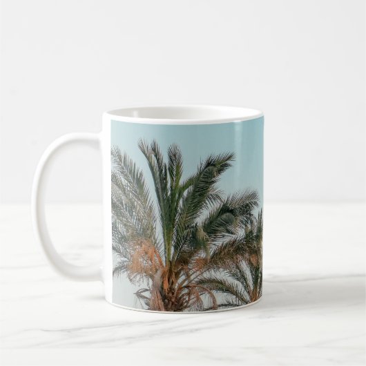 青空の下の緑のヤシの木 コーヒーマグカップ (左)