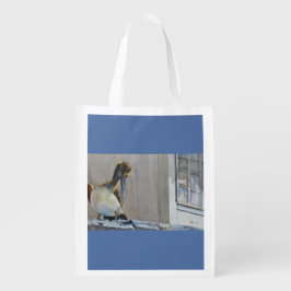 魚の市場の屋根の上の若いペリカン食べ物を待っている エコバッグ